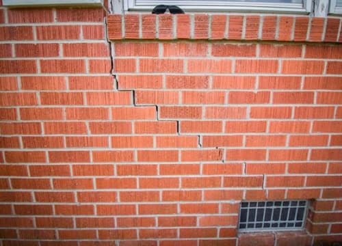 Stair-step cracks running through a brick wall