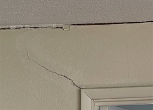 Drywall crack spreading above a door frame